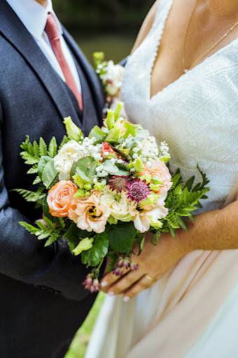 Deux mariés qui tiennent un bouquet de fleurs blanches et oranges