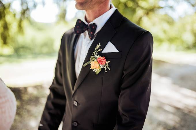 Boutonnière de marié en fleurs oranges et blanches